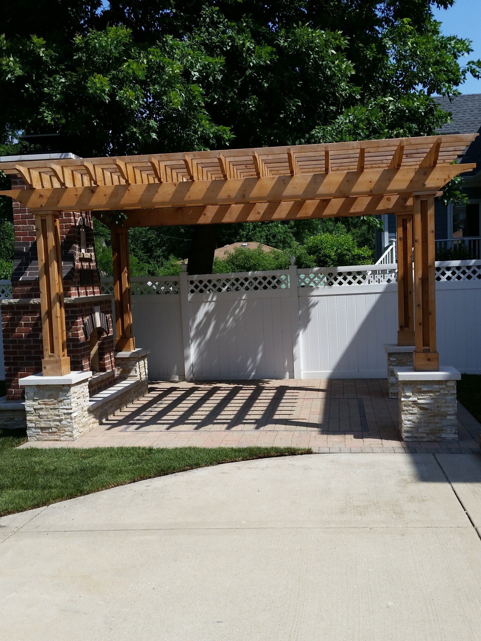 A wooden pergola is in the middle of a driveway