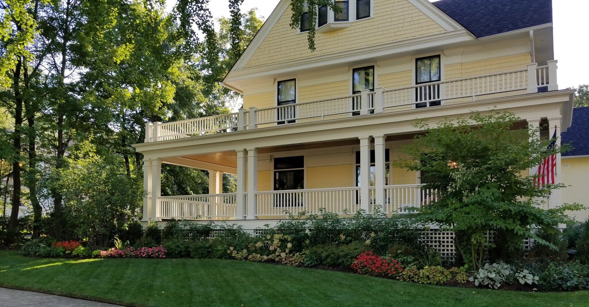 A large yellow house with a blue roof and a large porch