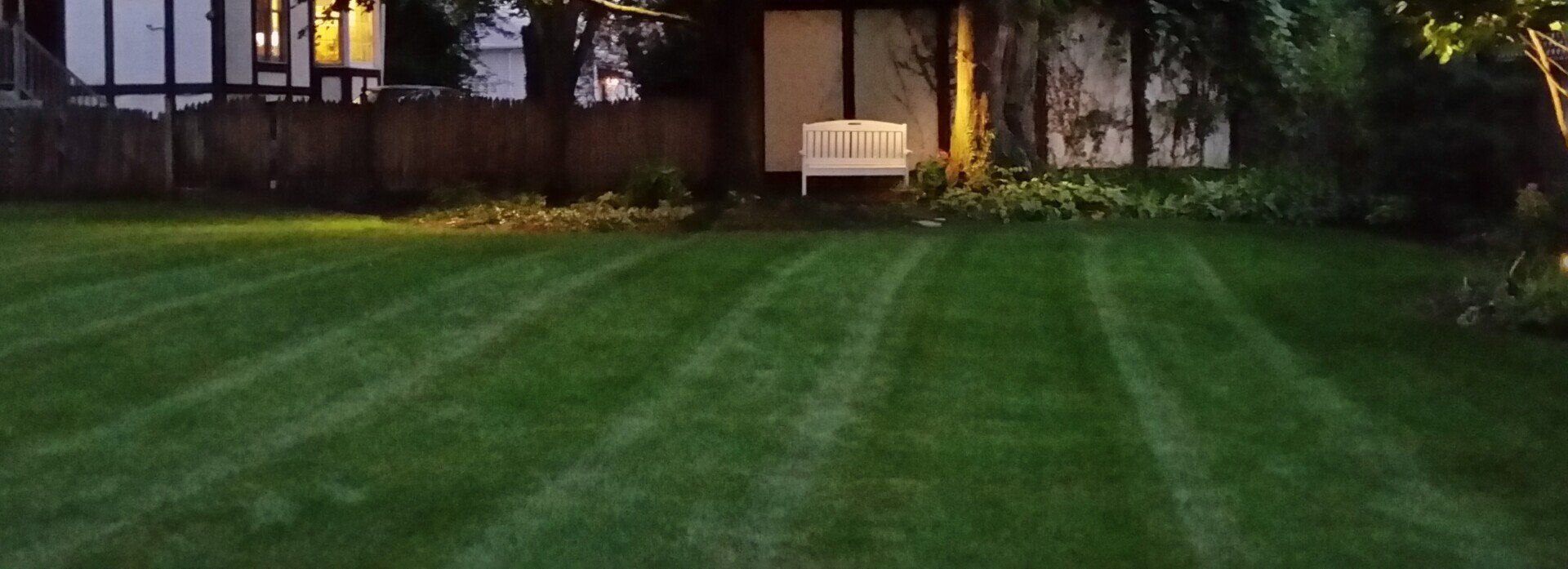 A lush green lawn in front of a house at night.