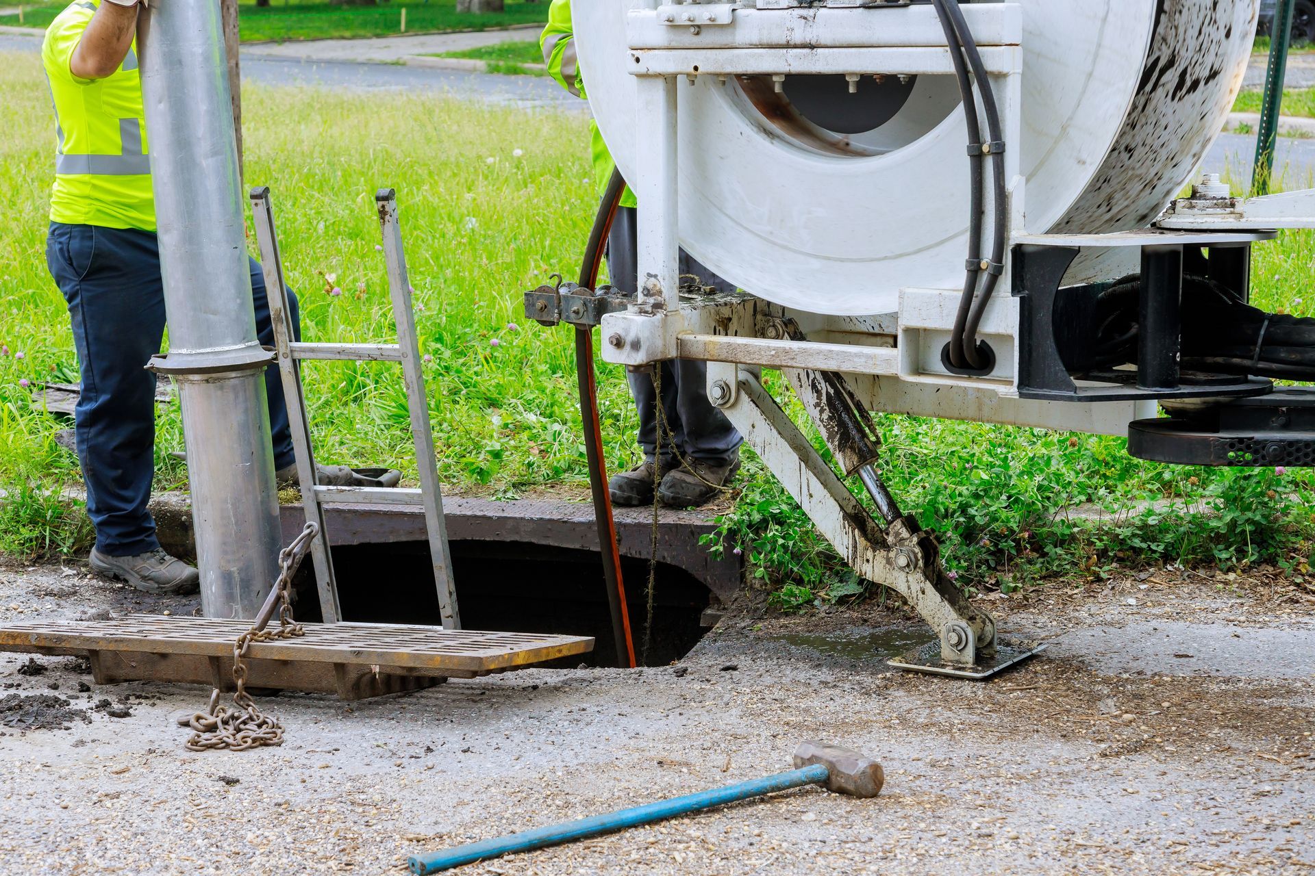 A man is standing next to a machine that is cleaning a manhole.