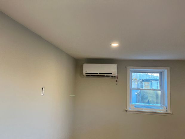 Woman using smartphone to control air conditioner in living room.
