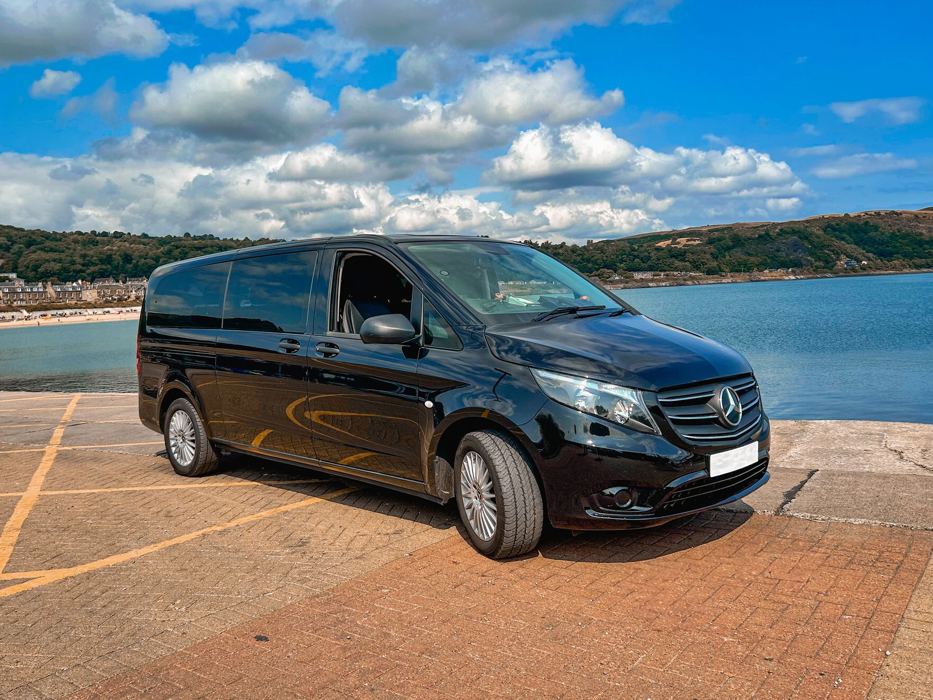 Luxury Black Mercedes vehicle sitting at the beach facing the camera.