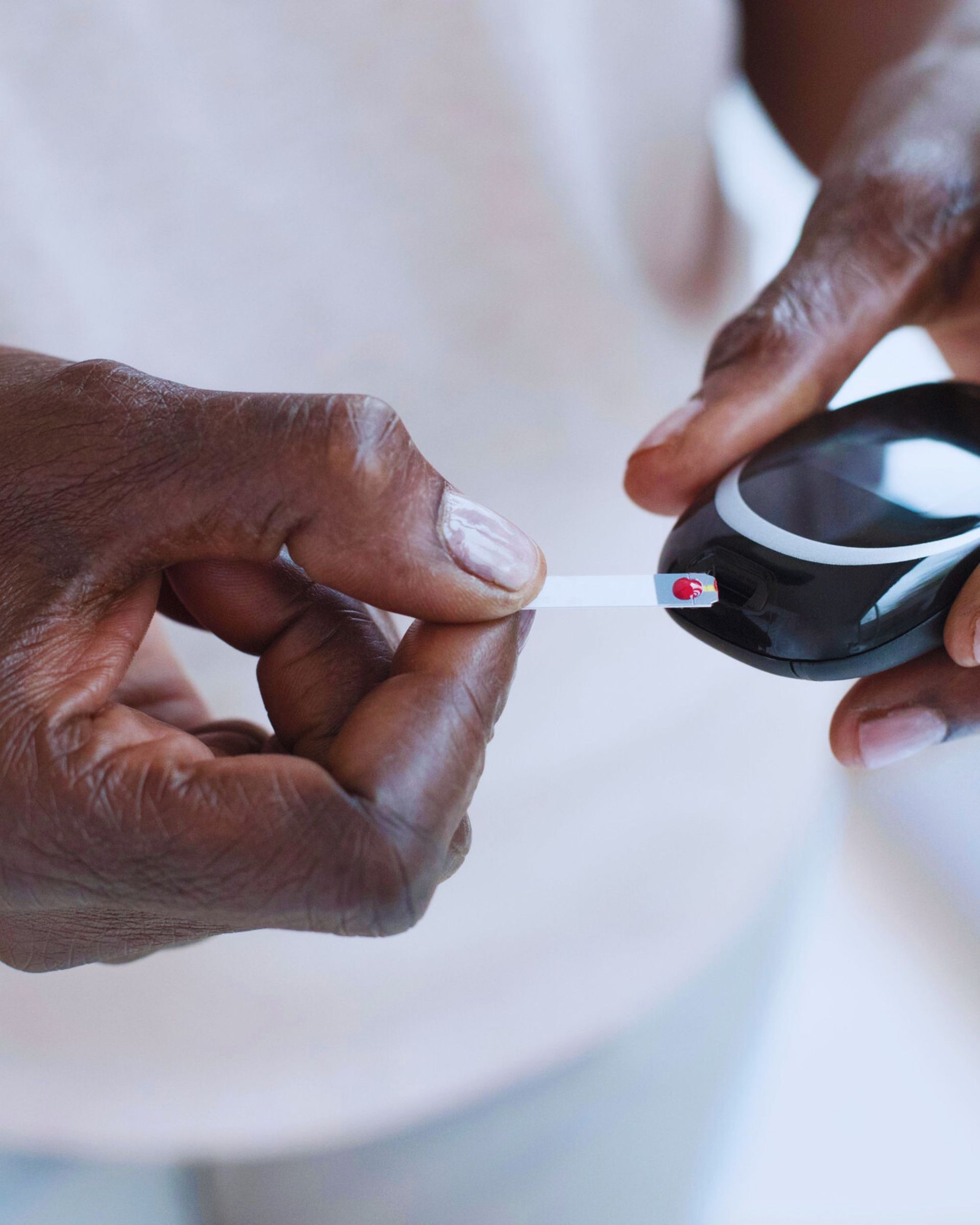 Person testing blood glucose with a blood glucose meter, using a test strip.