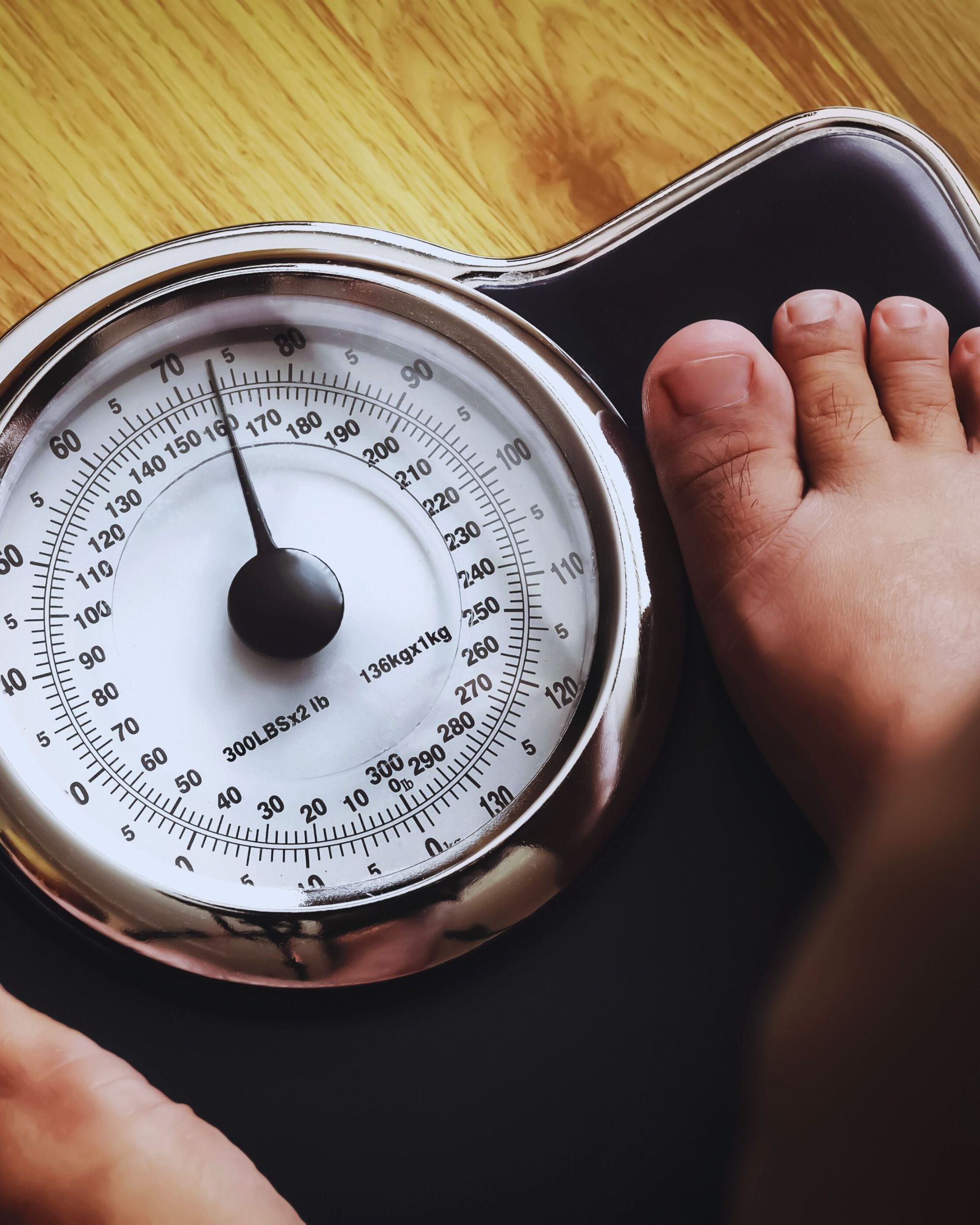 Person's foot on a black scale. The dial reads a weight in pounds.