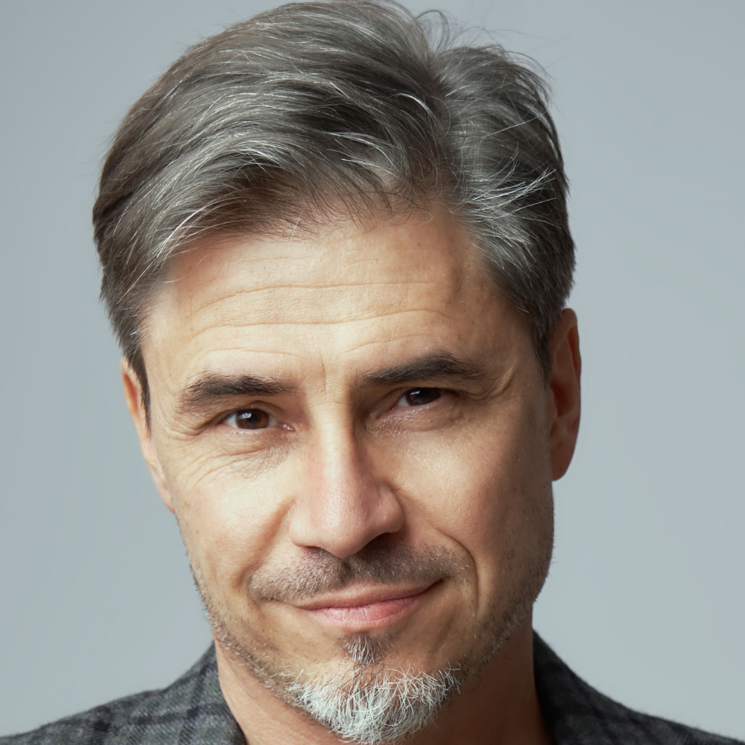 Man with graying hair and goatee, smiling, close-up shot.
