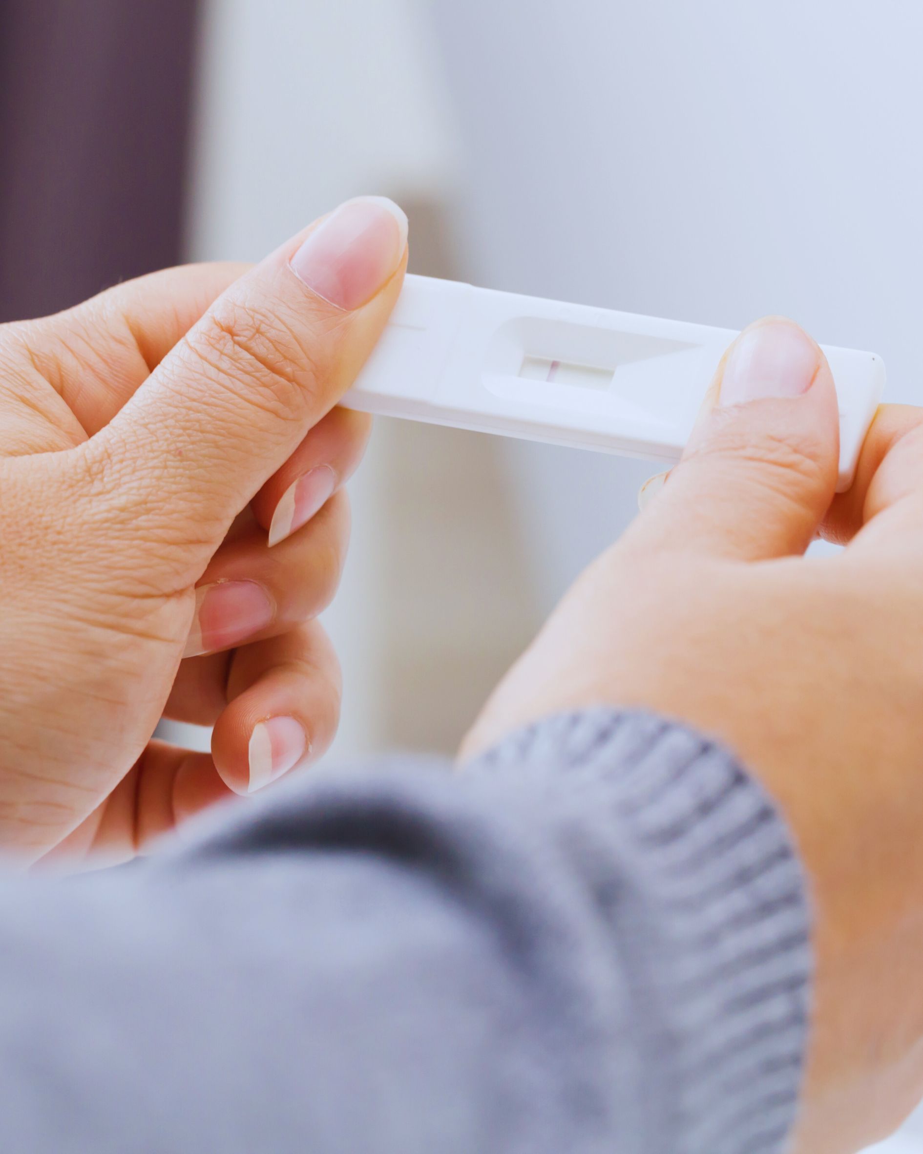 Hands holding a pregnancy test; awaiting the result.