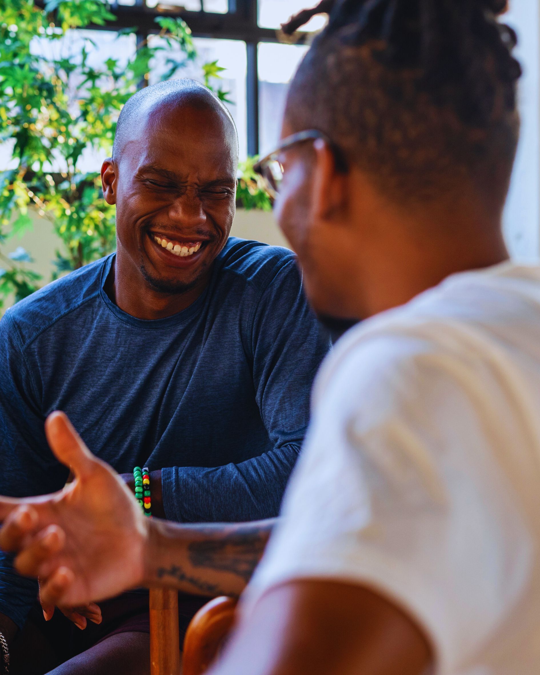 Two men laughing, indoors, one gesturing.