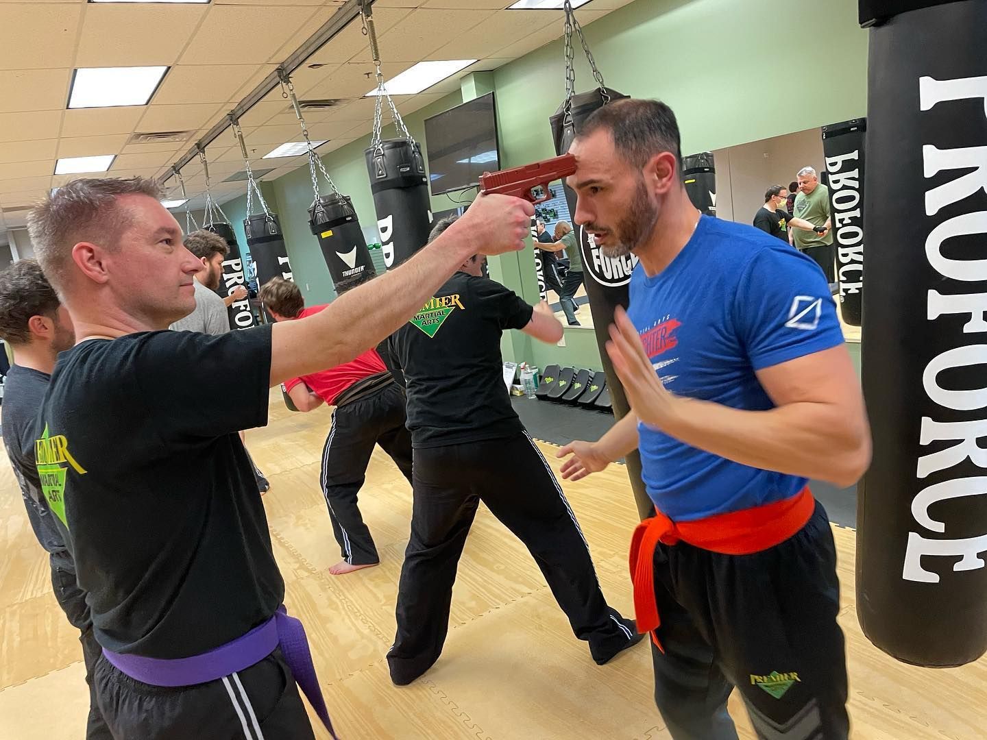 A group of men are practicing martial arts in a gym.