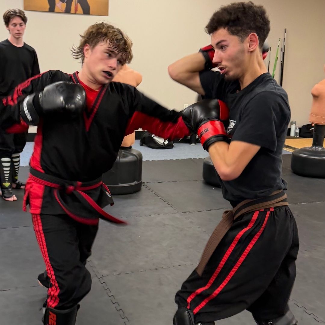 Two young men are practicing karate on a mat