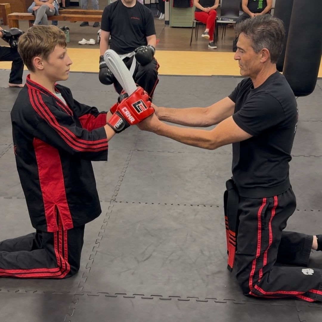 A group of men are practicing karate in a gym.