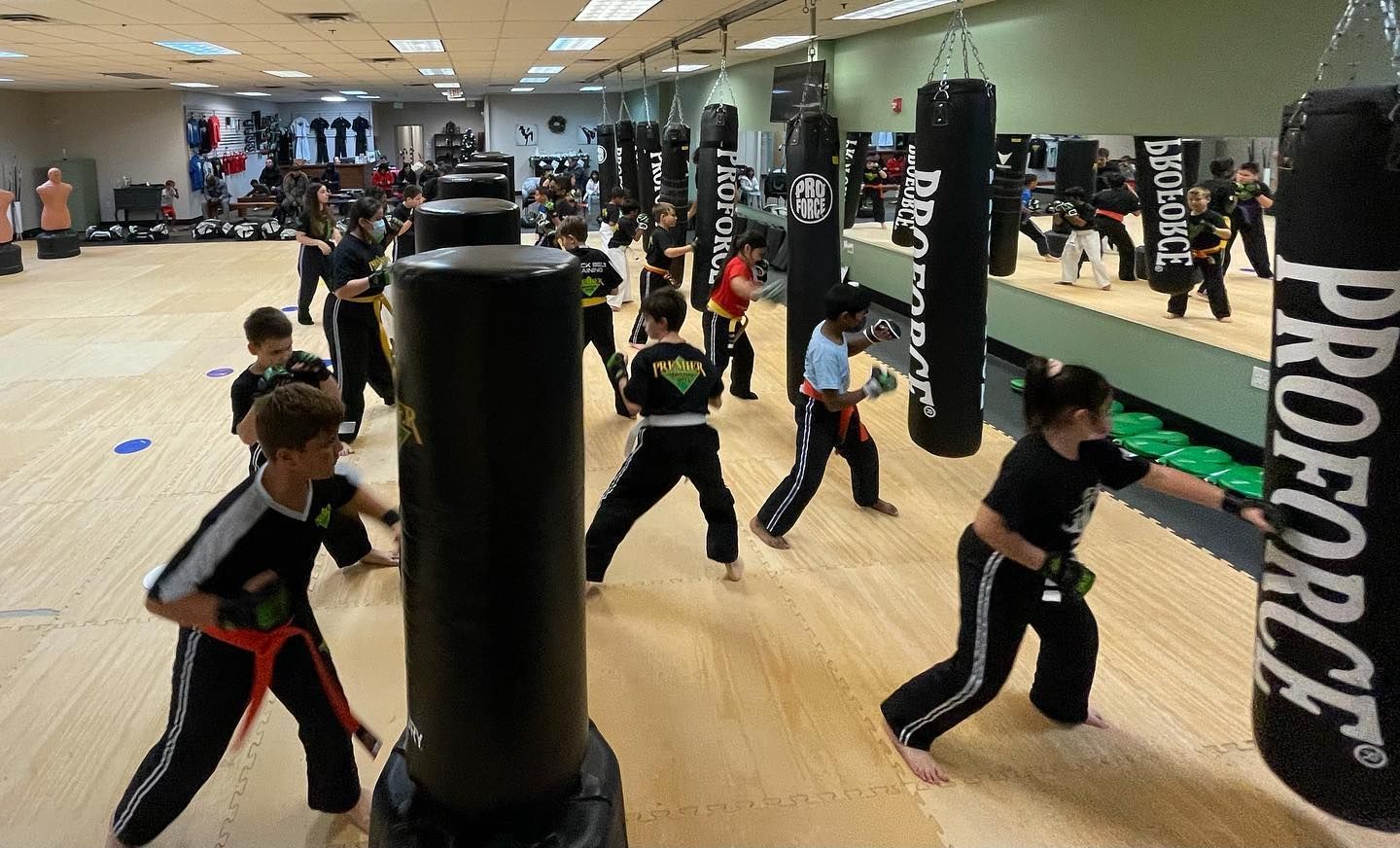 A group of young boys are sitting on a mat in front of a drink machine