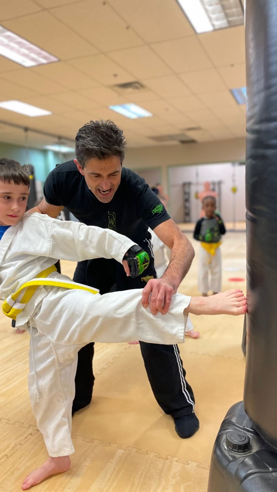 a little boy with boxing gloves punching a mat bag