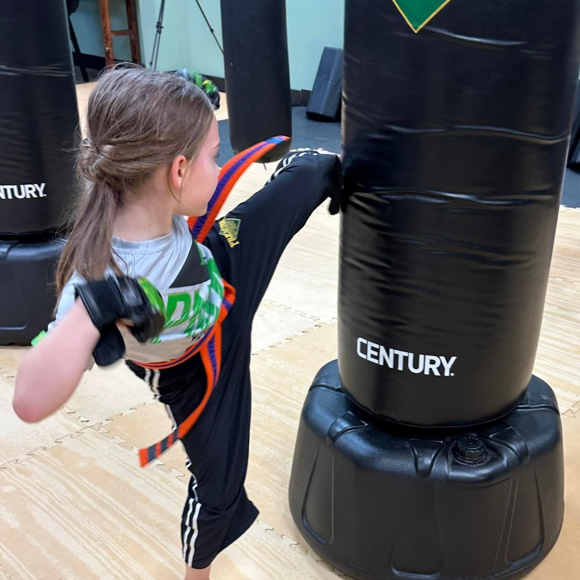 A group of children are practicing karate with a teacher in a gym.
