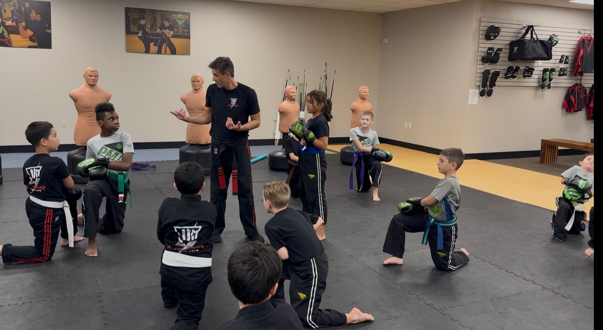 a little boy with boxing gloves punching a mat bag