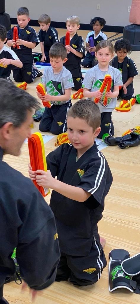 A group of young boys are kneeling on the floor holding toys.
