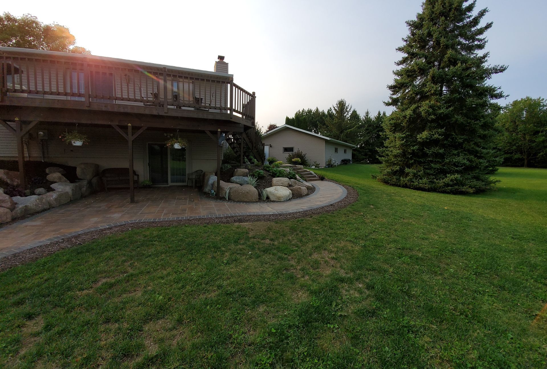 The backyard of a house with a large deck and patio.