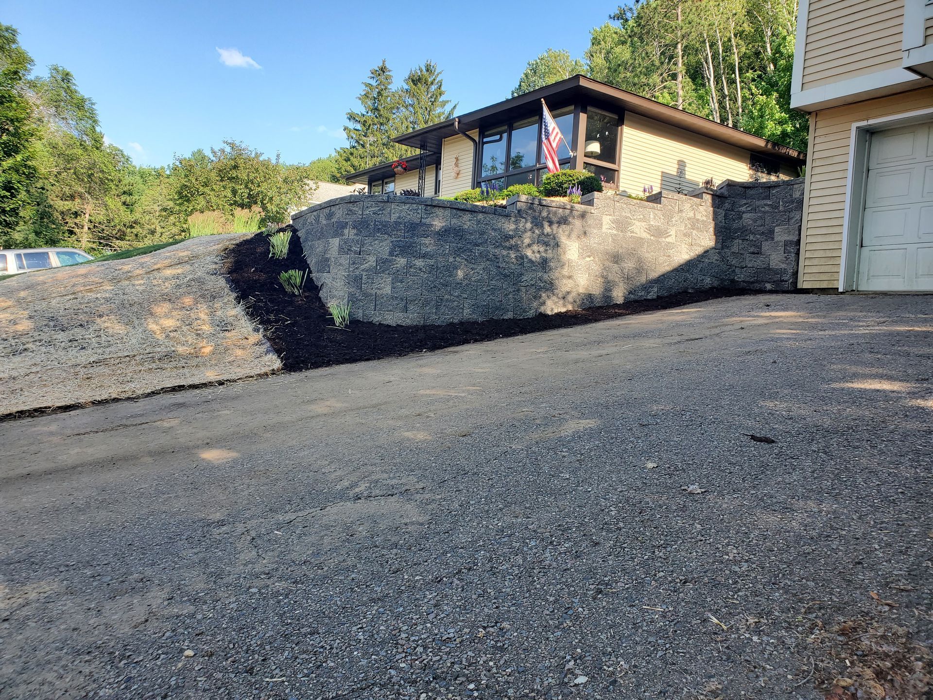 A large rock is sitting on the side of a road in front of a house.