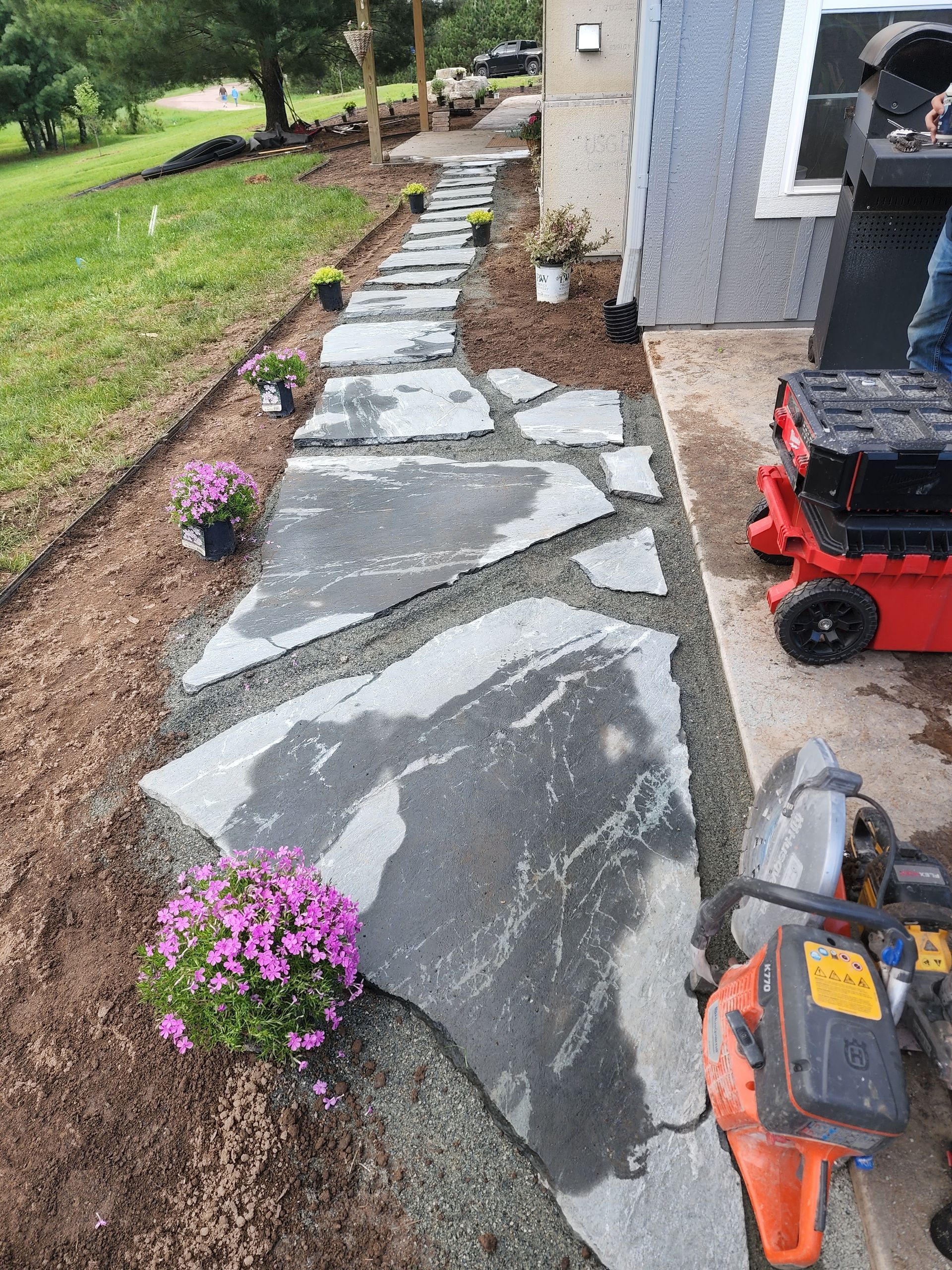 A stone walkway is being built in front of a house.