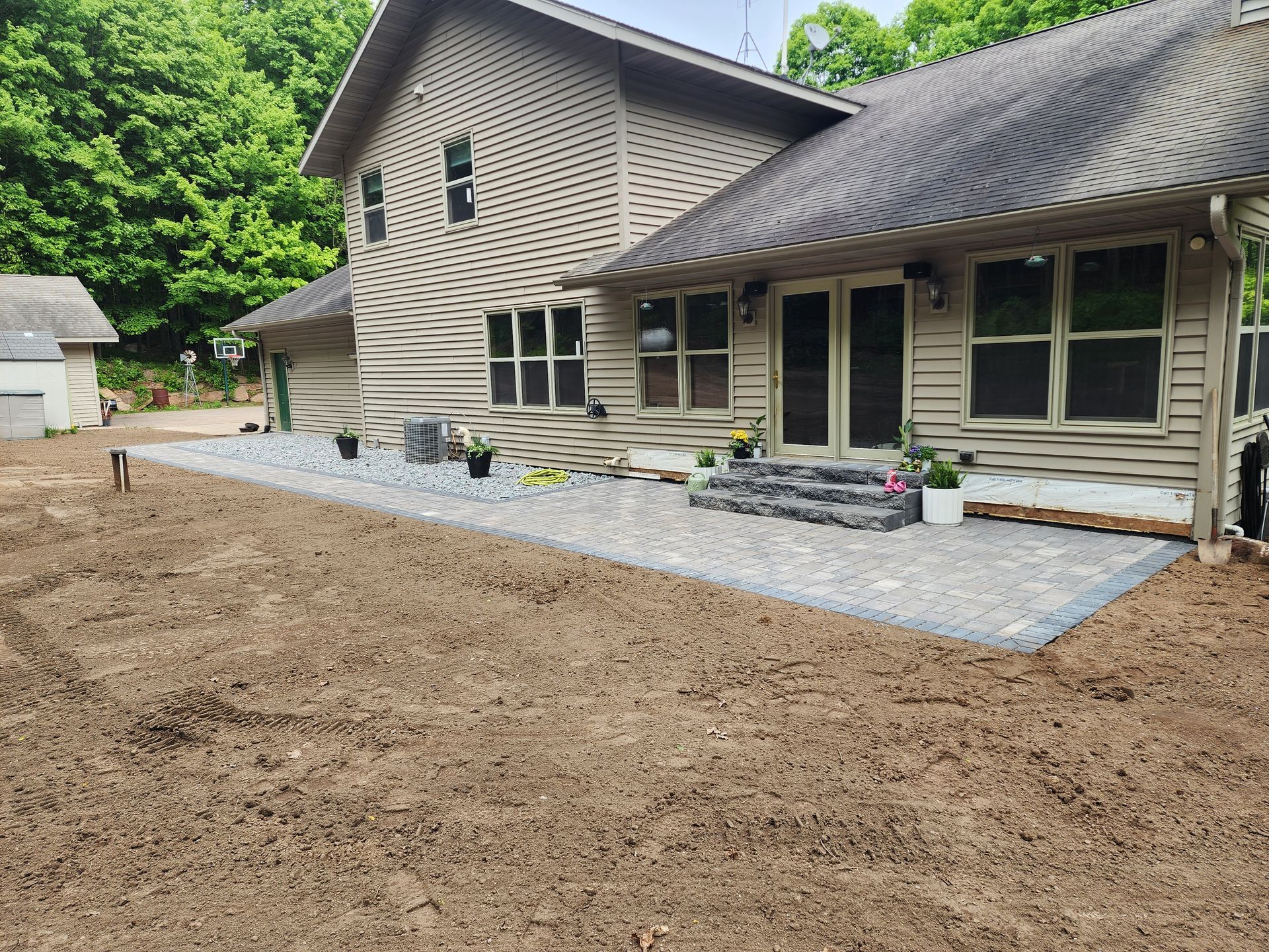A new brick patio installed behind a tan home in Weston, Wisconsin
