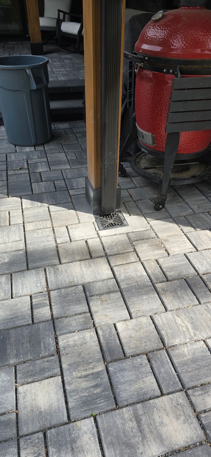A patio with a grill and a trash can on it.