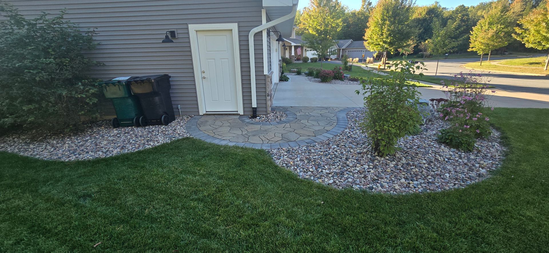 A house with a patio and a trash can in front of it.