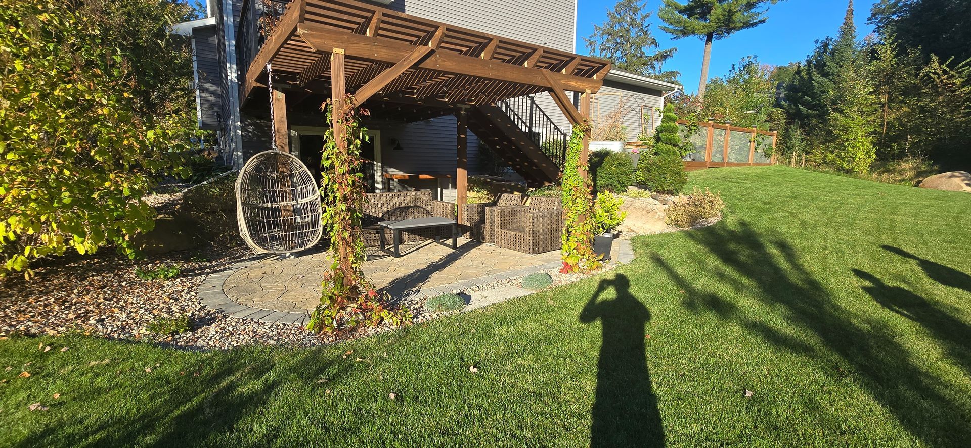 A shadow of a person is cast on the grass in front of a house.