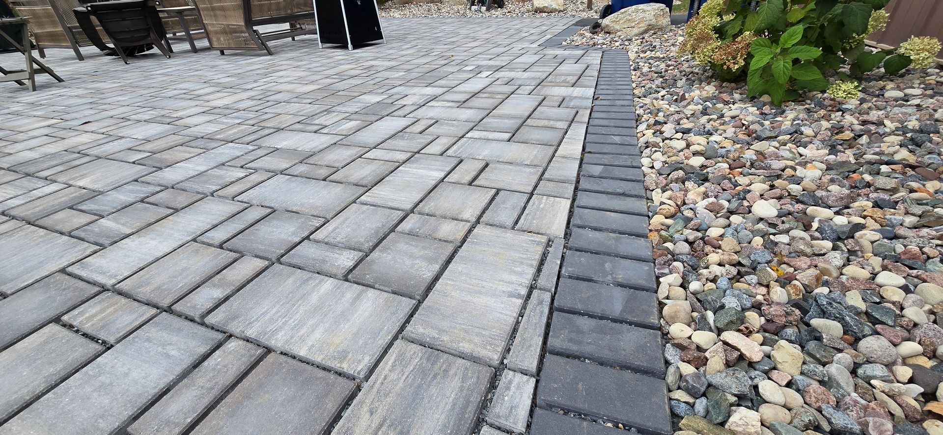 A patio with a brick walkway and gravel in the background.