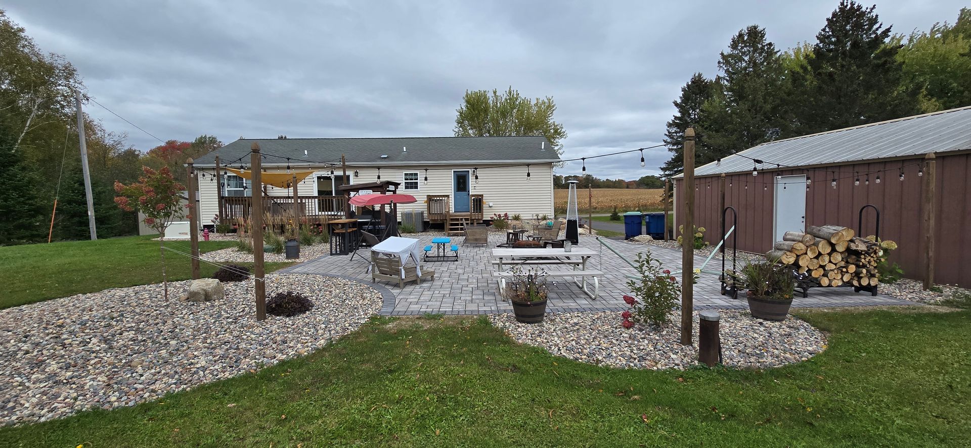 A backyard with a patio, lawn, and shed under a cloudy sky.