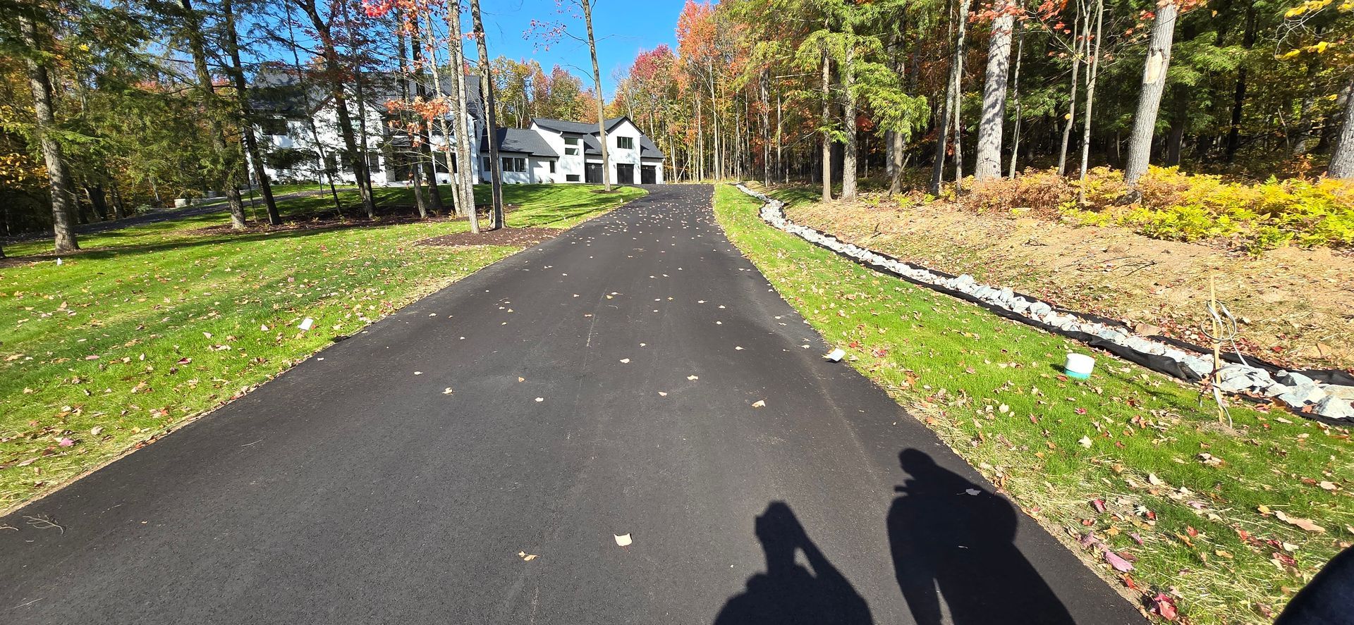 A shadow of a person is cast on the side of a road.