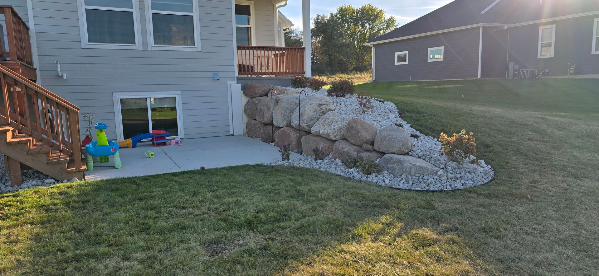 There is a large rock wall in the backyard of a house.