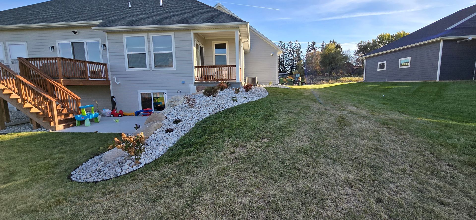 The backyard of a house with a large lawn and a deck.