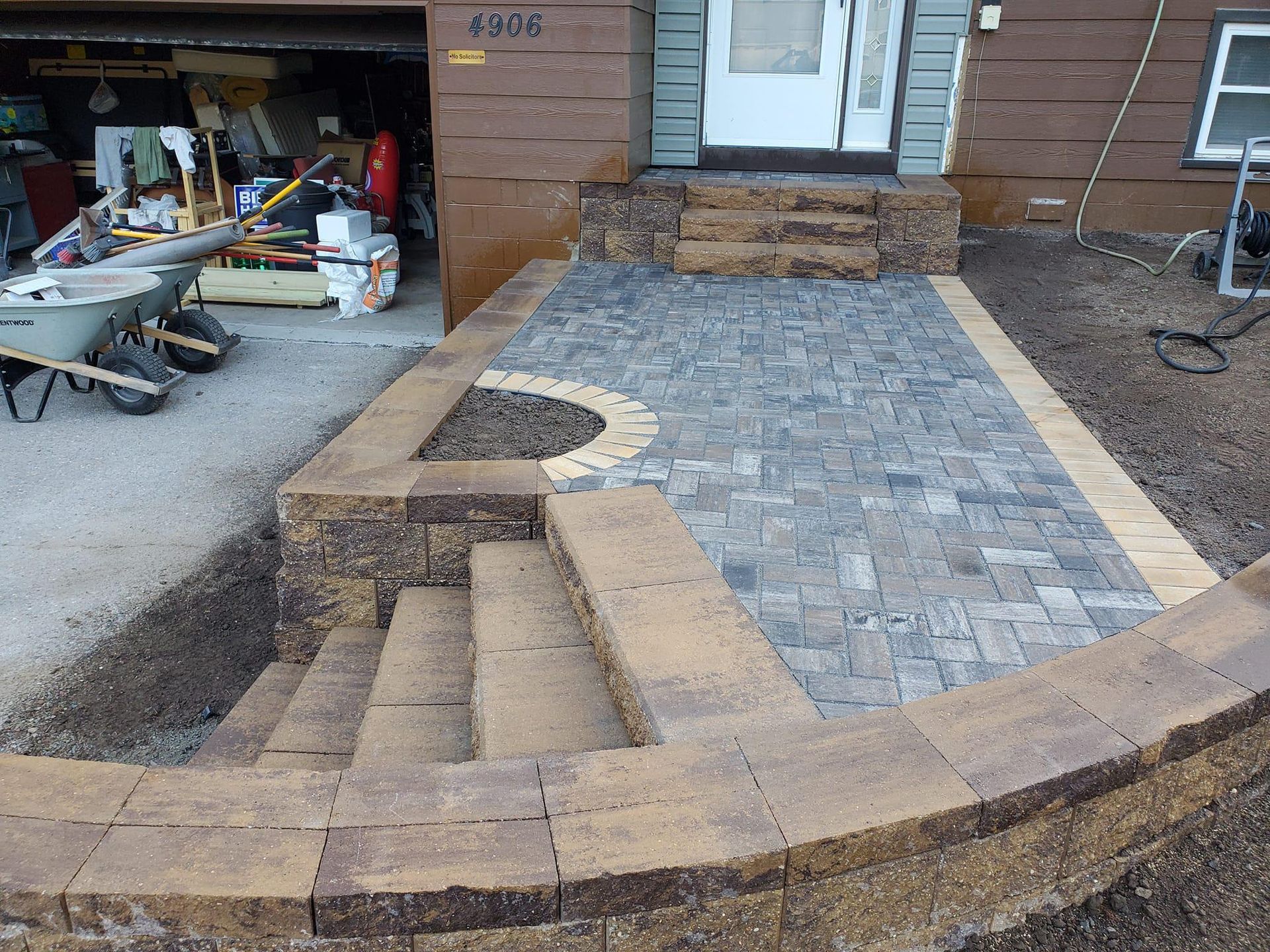 A brick walkway is being built in front of a house