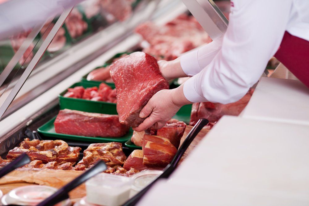 Butcher Getting Cut of Meat From the Display Cabinet — Butcher in Wauchope, NSW