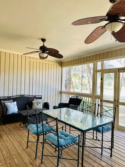 A screened in porch with a table and chairs and ceiling fans