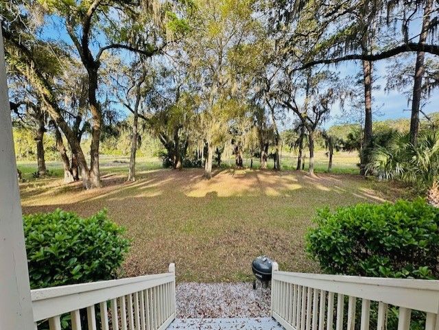 A view of a lush green field and trees from a porch