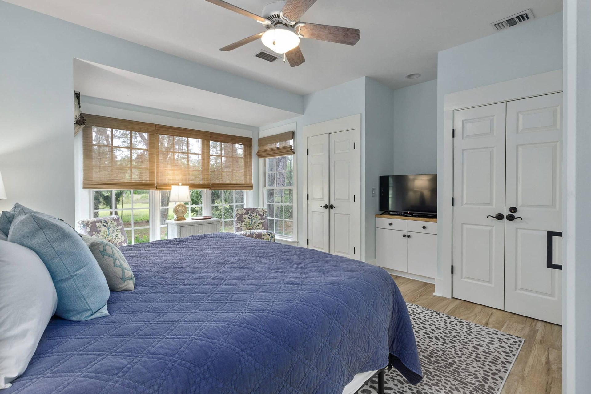 A bedroom with a large bed , a ceiling fan , and a television.