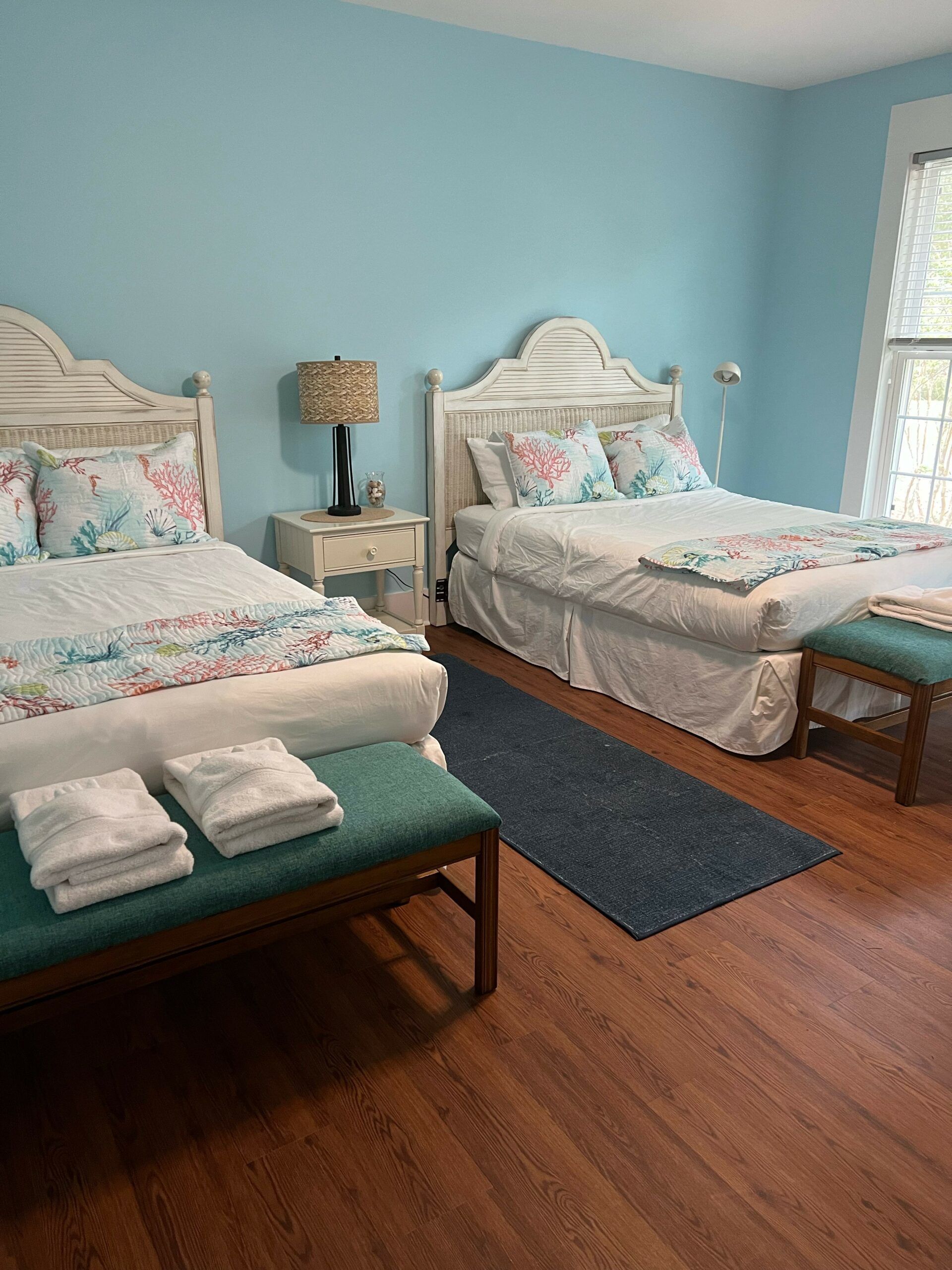 A bedroom with two beds , a bench and a window.