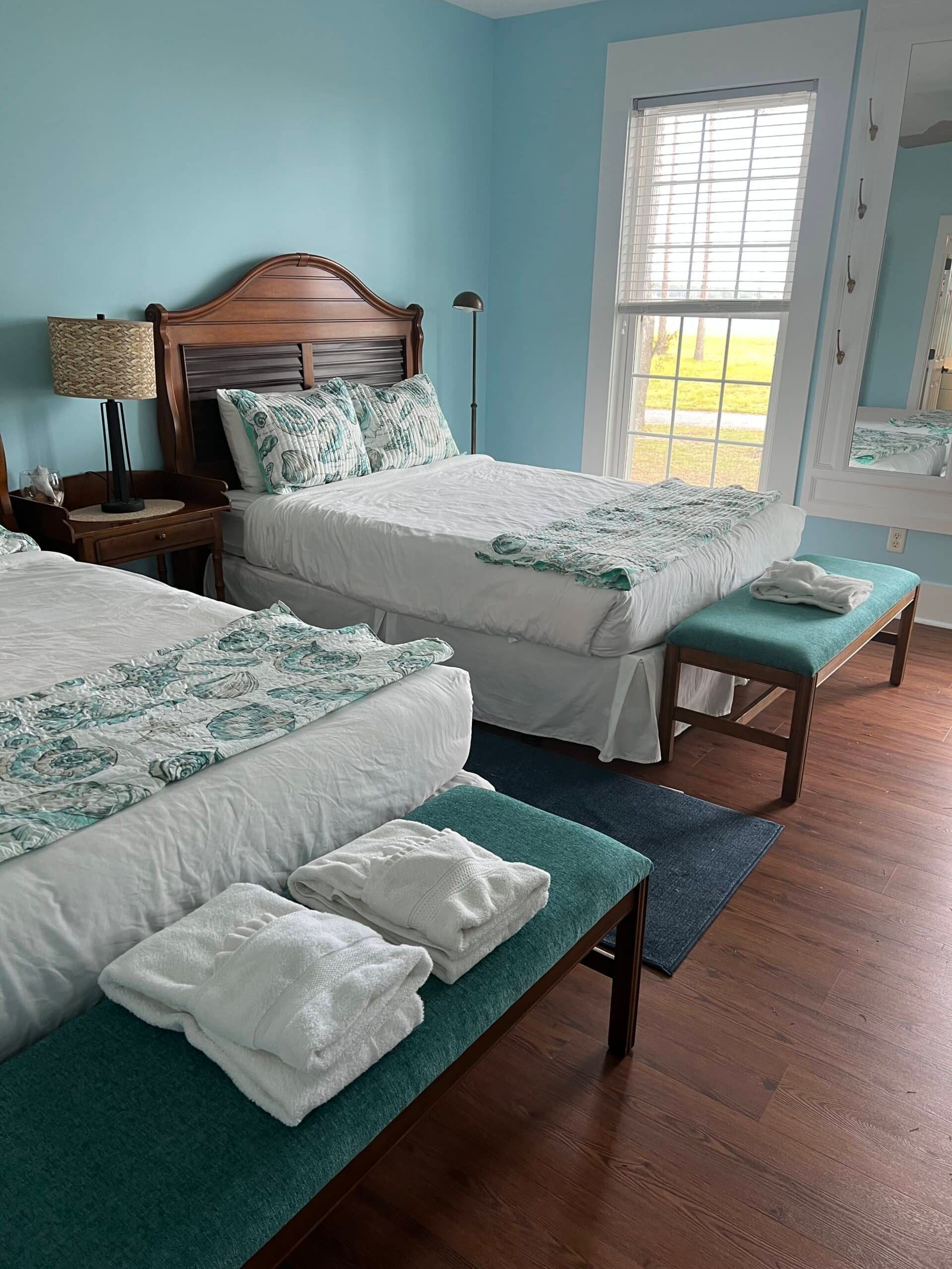 A bedroom with two beds , a bench and a window.