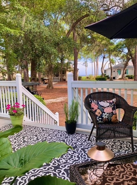 A patio with a wicker chair , table , and umbrella.