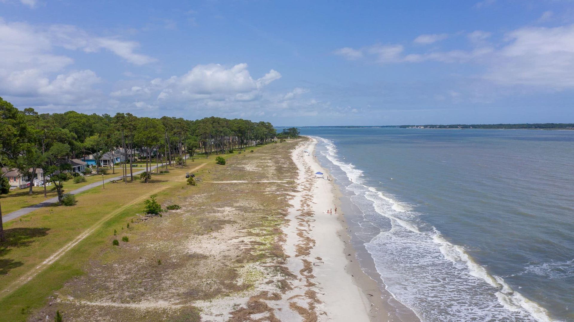 An aerial view of a beach with waves crashing on the shore.