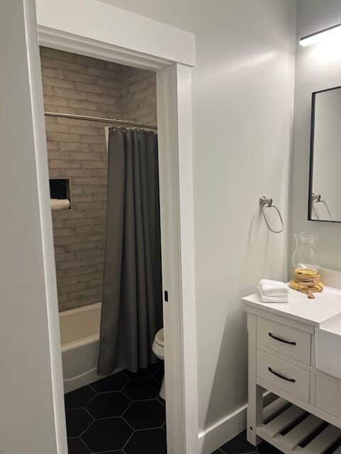 A bathroom with a sink , toilet , shower and mirror.