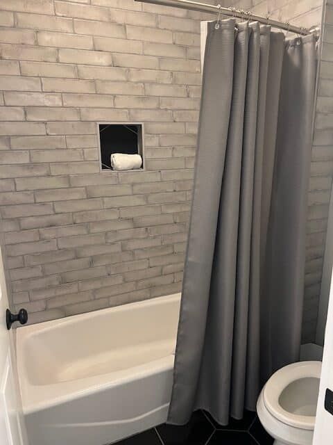 A bathroom with a bathtub , toilet and shower curtain.