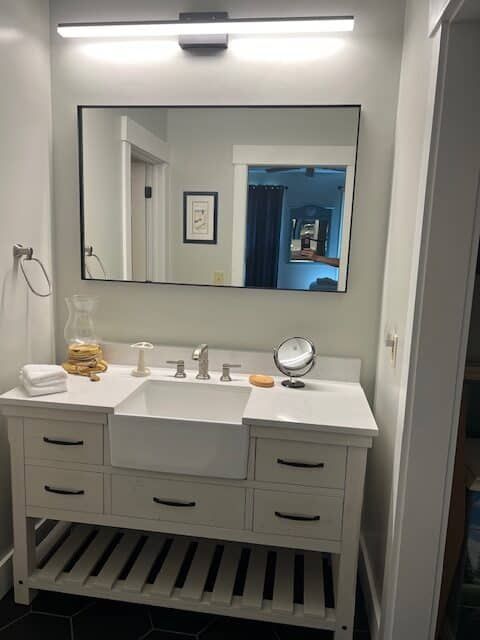 A bathroom with a sink , mirror , and drawers.