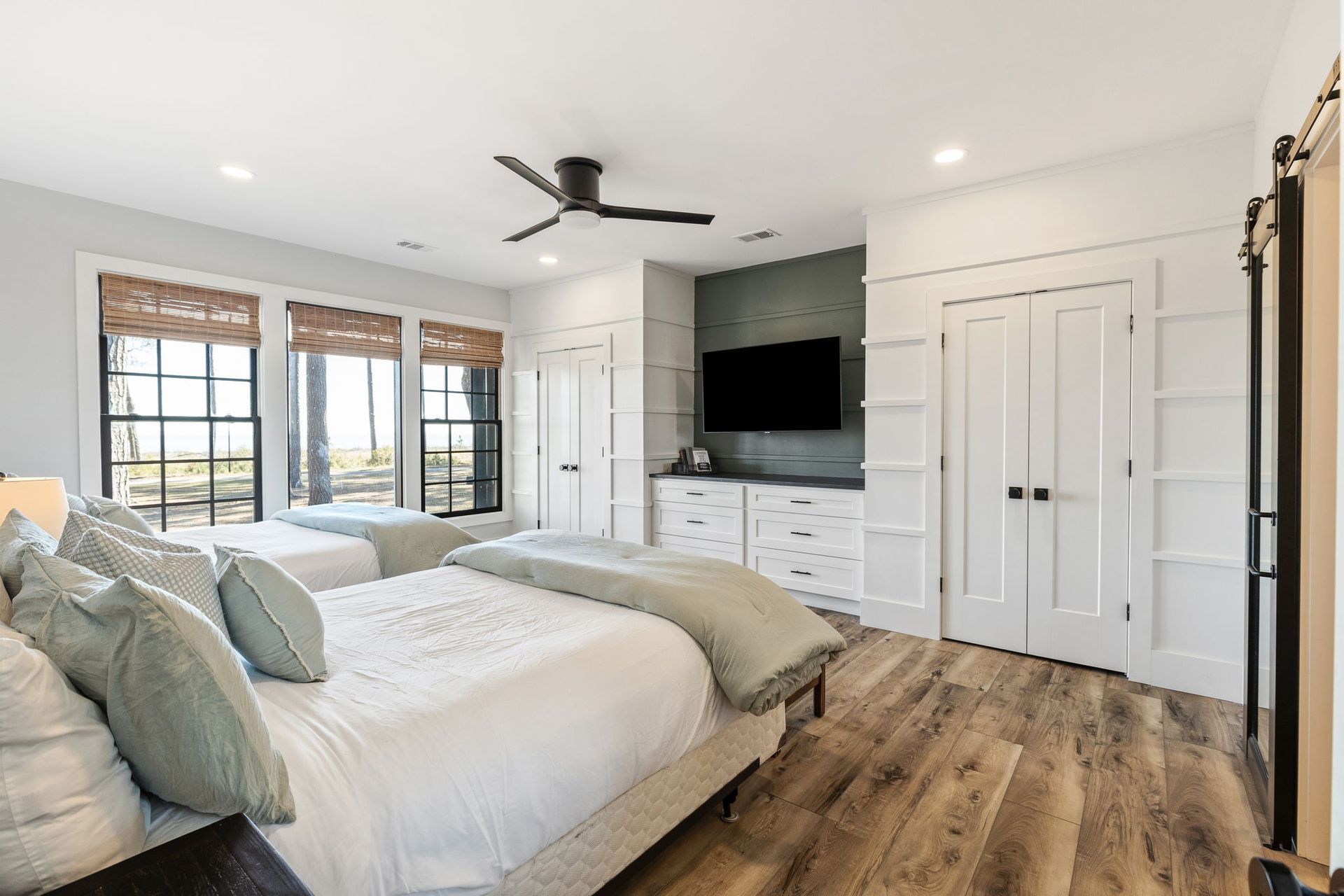 A bedroom with two beds , a ceiling fan , and a flat screen tv.