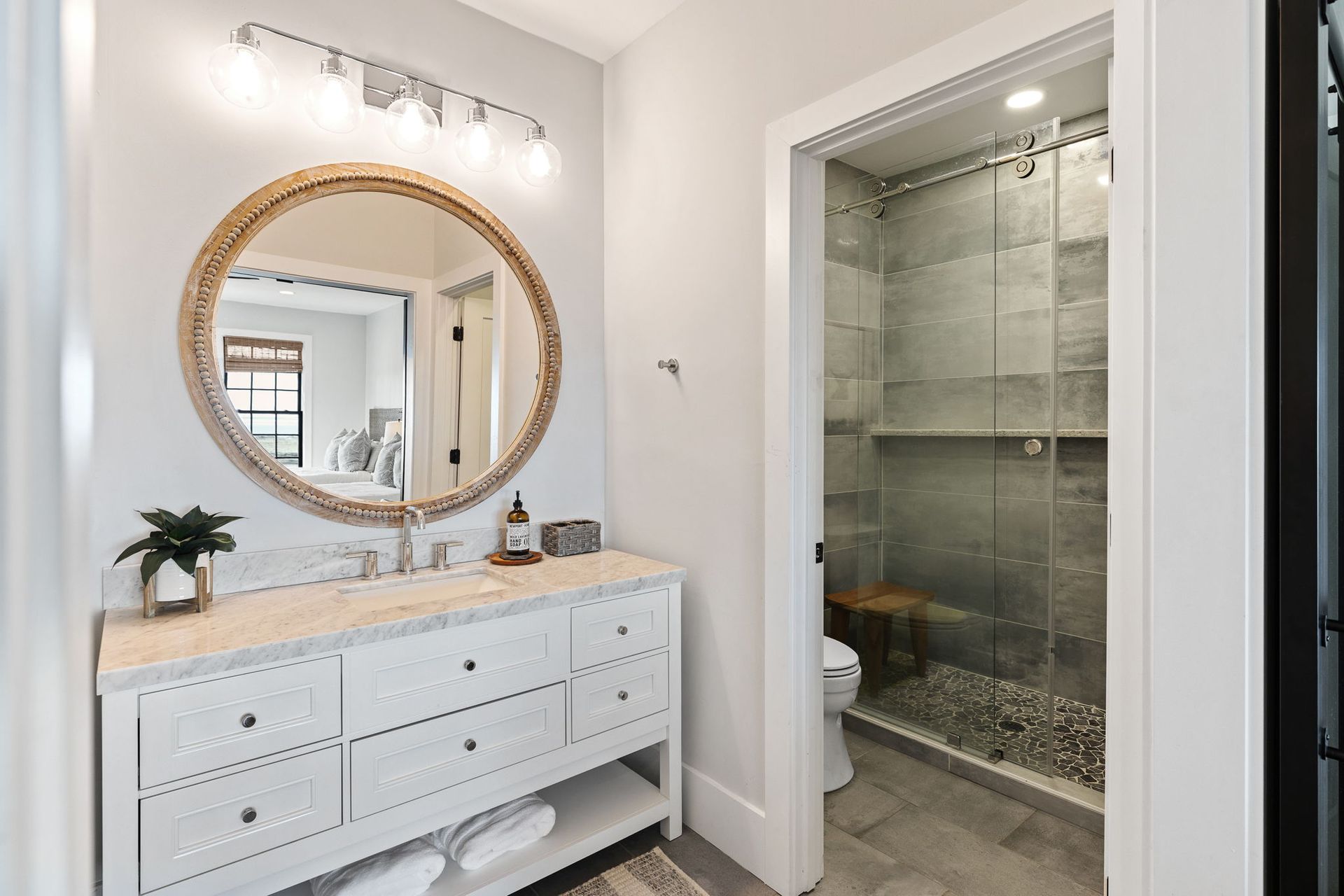 A bathroom with a vanity , mirror , toilet and shower.