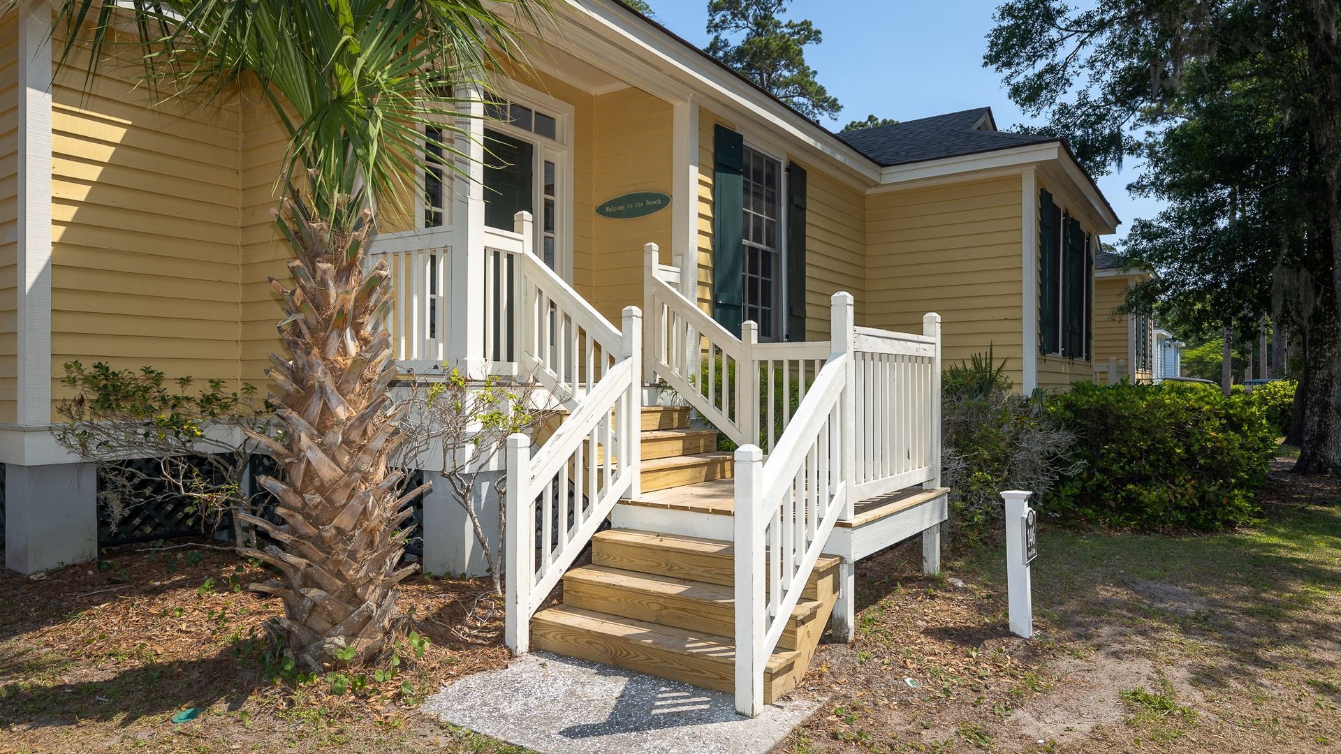 A yellow house with a white porch and stairs