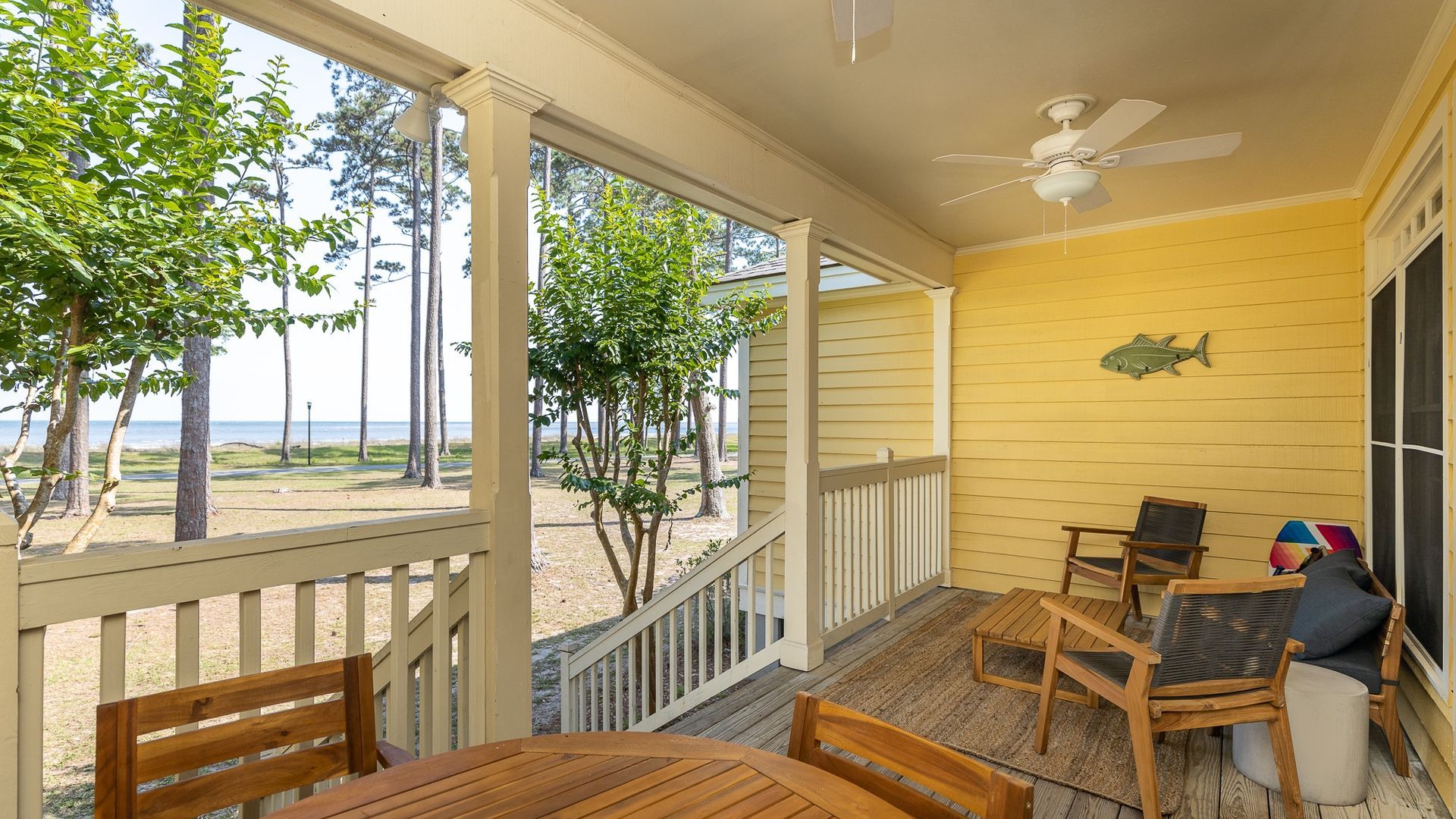 A porch with a table and chairs and a ceiling fan.