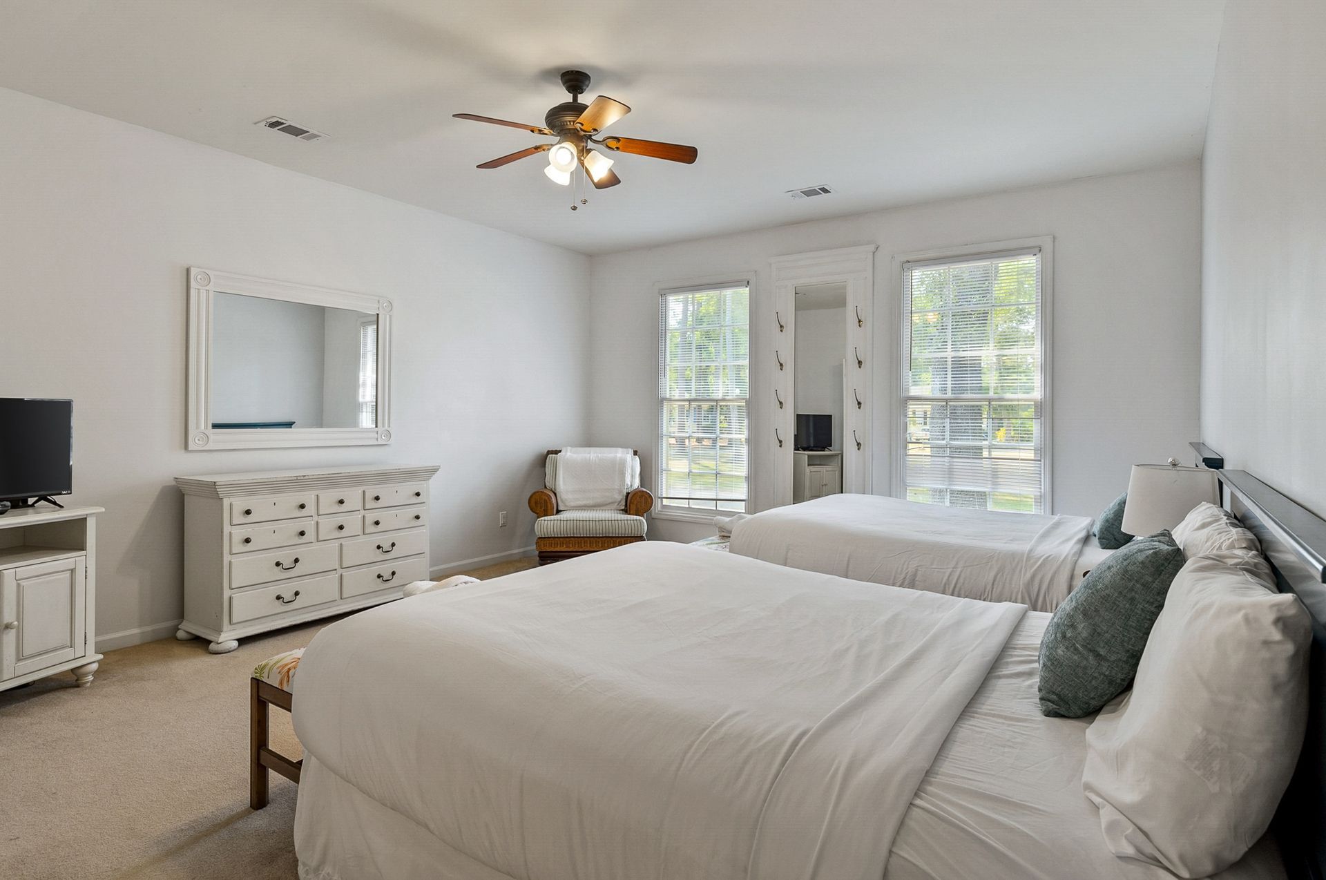 A bedroom with two beds and a ceiling fan.