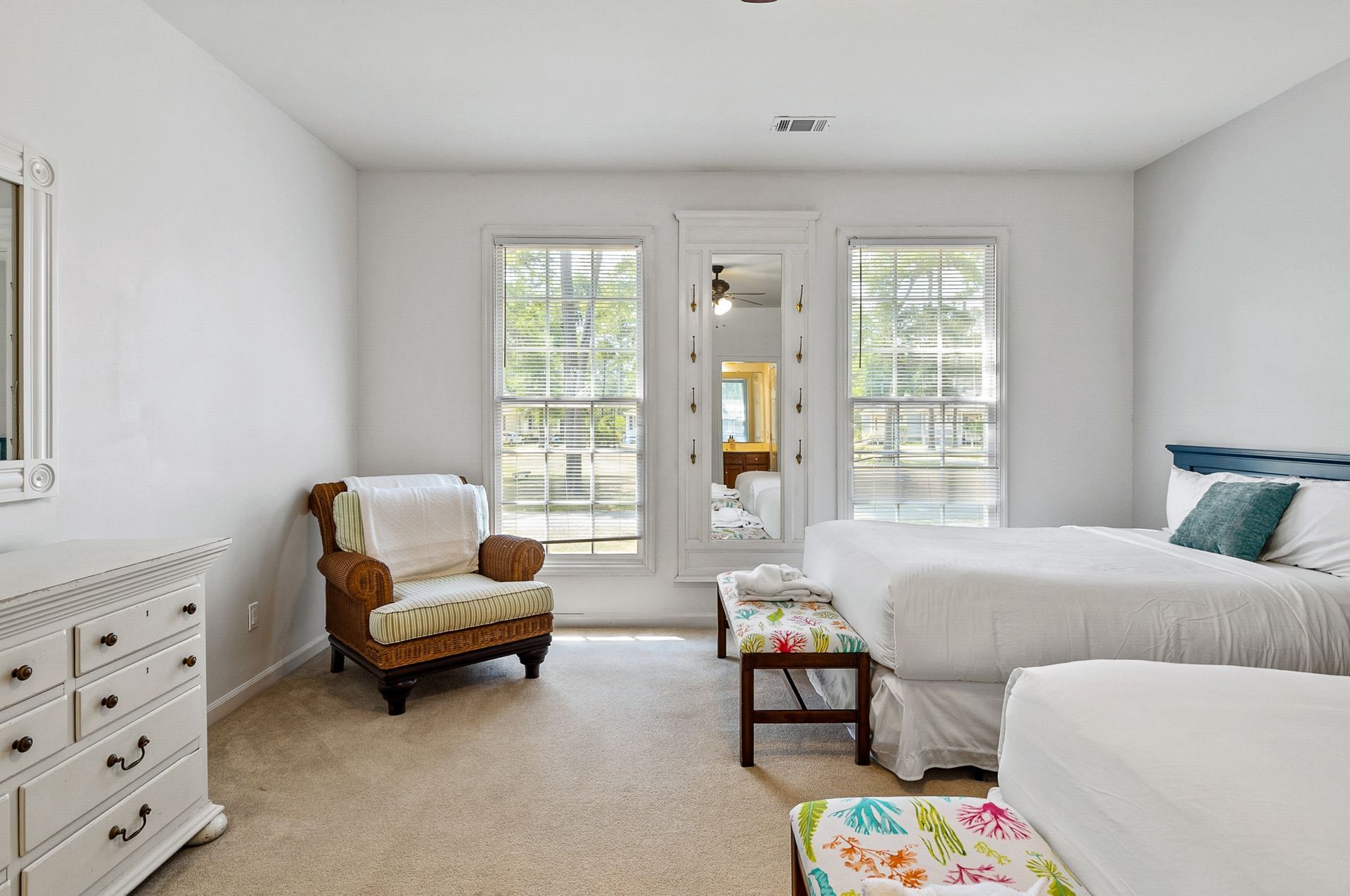 A bedroom with two beds , a chair , a dresser and a mirror.