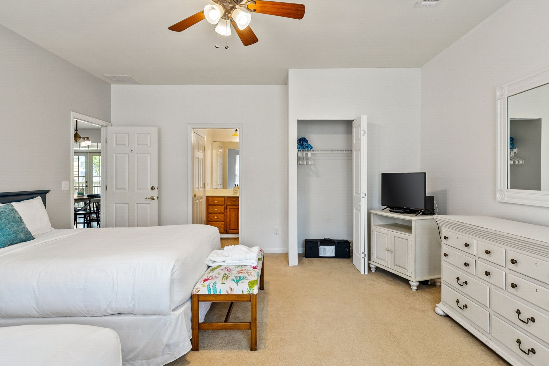 A bedroom with two beds , a dresser , a television and a ceiling fan.